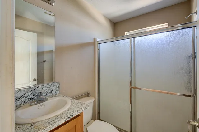a bathroom with a granite countertop sink toilet and shower