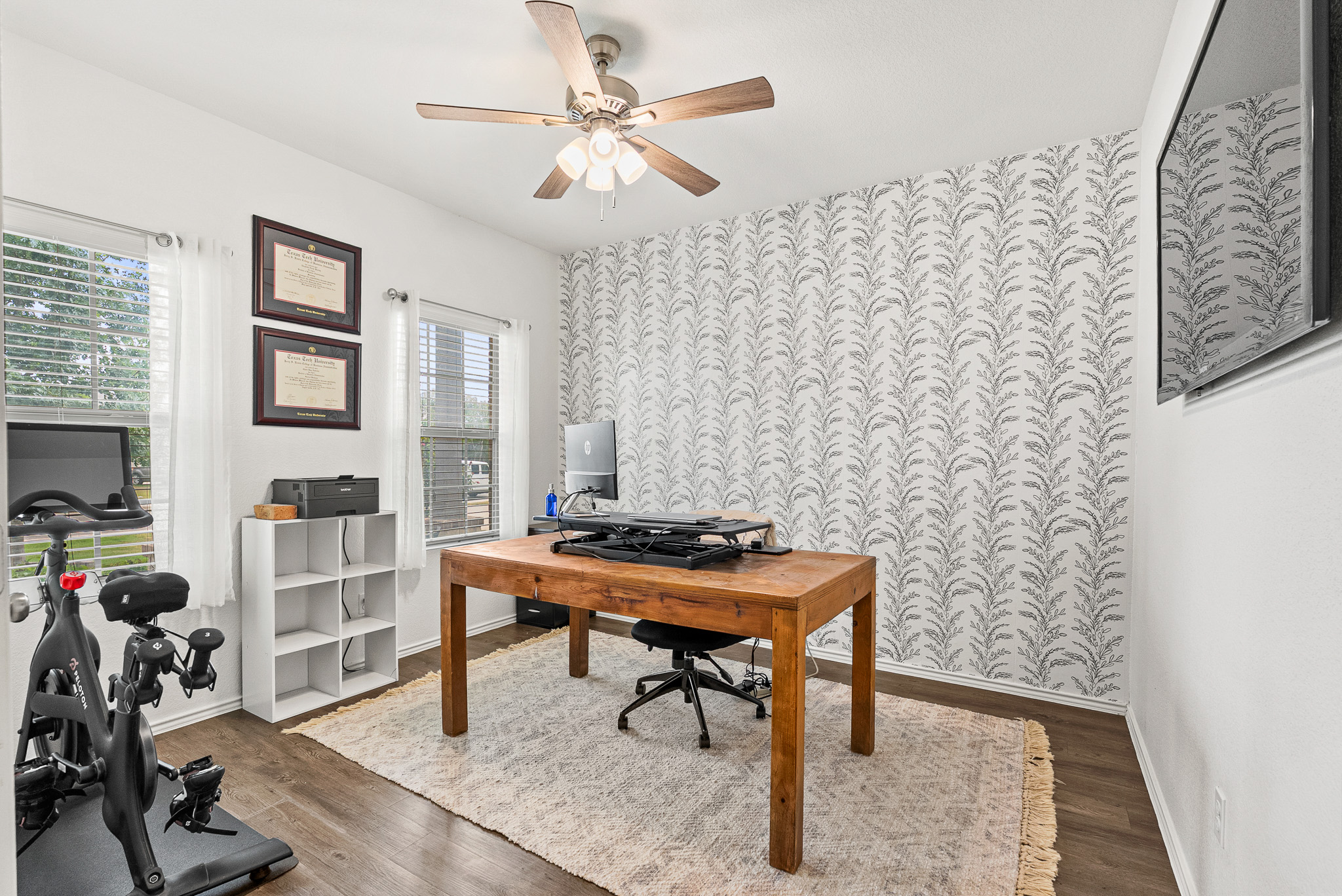 136 Copper Lane Kyle, TX 78640 - Photo 31 of 33 Home office featuring wallpapered walls, dark wood-style floors, an accent wall, and a ceiling fan