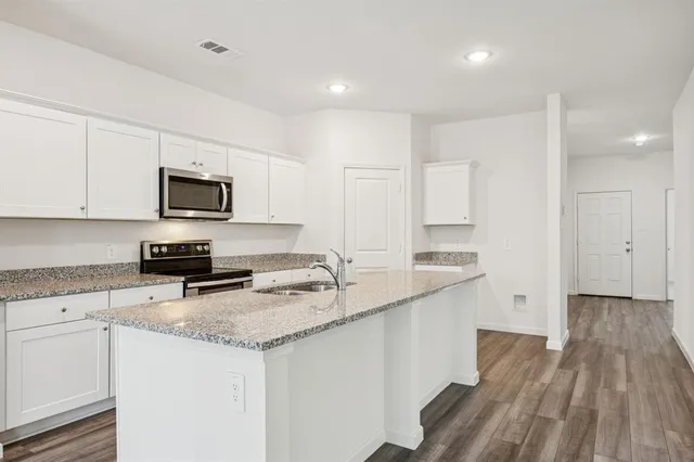 a kitchen with granite countertop a sink stainless steel appliances and white cabinets