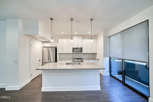 a large kitchen with stainless steel appliances kitchen island a large counter top and a refrigerator