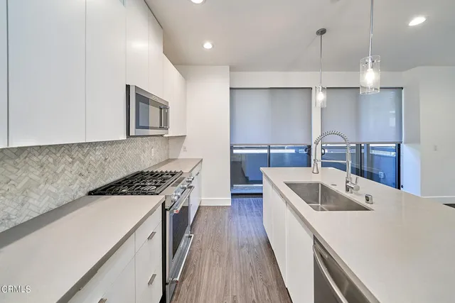 a kitchen with a sink stove and wooden floor