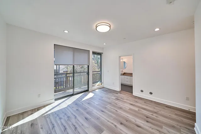 an empty room with wooden floor and natural light