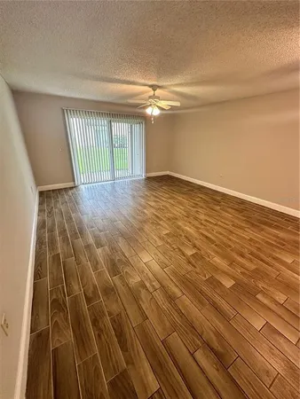 en empty room with wooden floor and fan