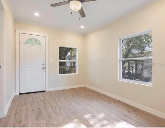 a view of an empty room with a window and wooden floor