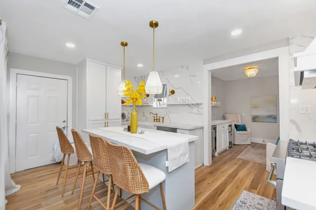 a kitchen with stainless steel appliances kitchen island granite countertop a table chairs and a refrigerator