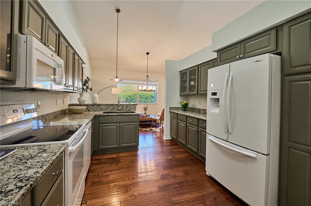 186 Muirfield Circle Naples, FL 34113 - Photo 7 of 36 a kitchen with stainless steel appliances granite countertop a refrigerator a sink dishwasher a stove and a dining table with wooden floor