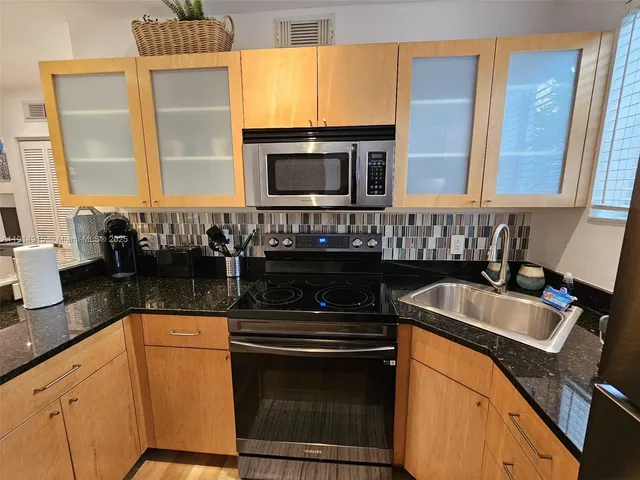 a kitchen with granite countertop a sink and a stove