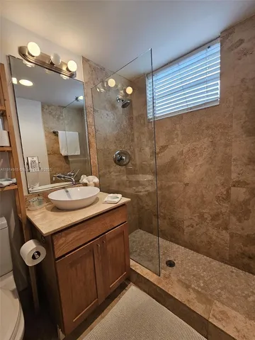 a bathroom with a sink a toilet a mirror and shower