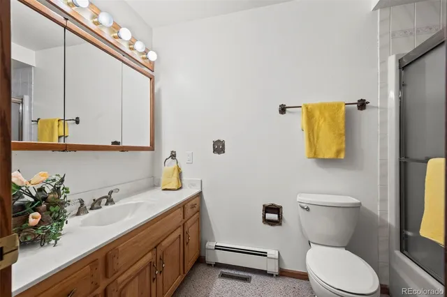 a bathroom with a granite countertop toilet sink and mirror