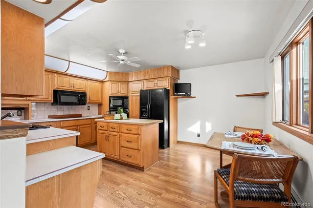 a kitchen with stainless steel appliances kitchen island granite countertop a sink dishwasher a stove and a refrigerator with wooden floor