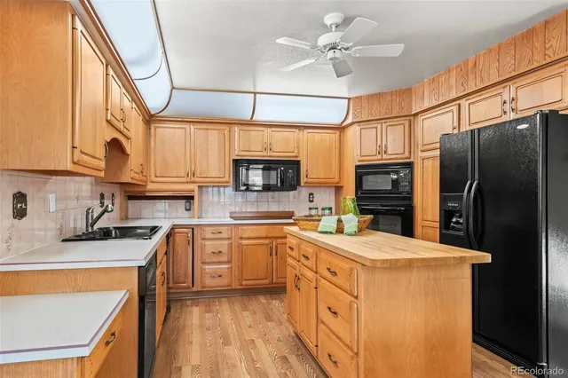 a kitchen with stainless steel appliances granite countertop a refrigerator a sink dishwasher a stove and white cabinets with wooden floor