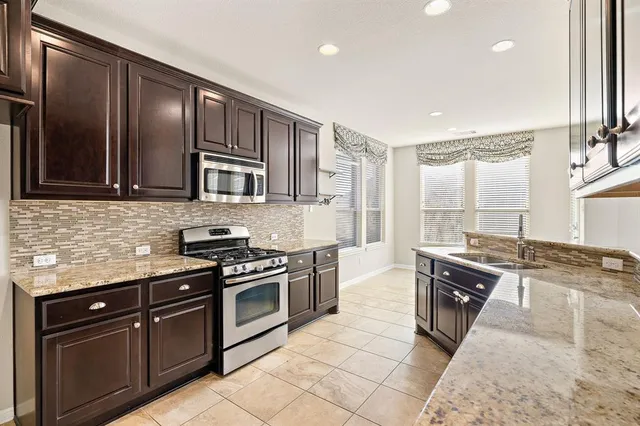 a kitchen with stainless steel appliances granite countertop wooden cabinets a stove top oven a sink and dishwasher
