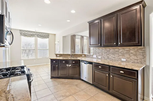 a kitchen with stainless steel appliances granite countertop a stove a sink and a microwave