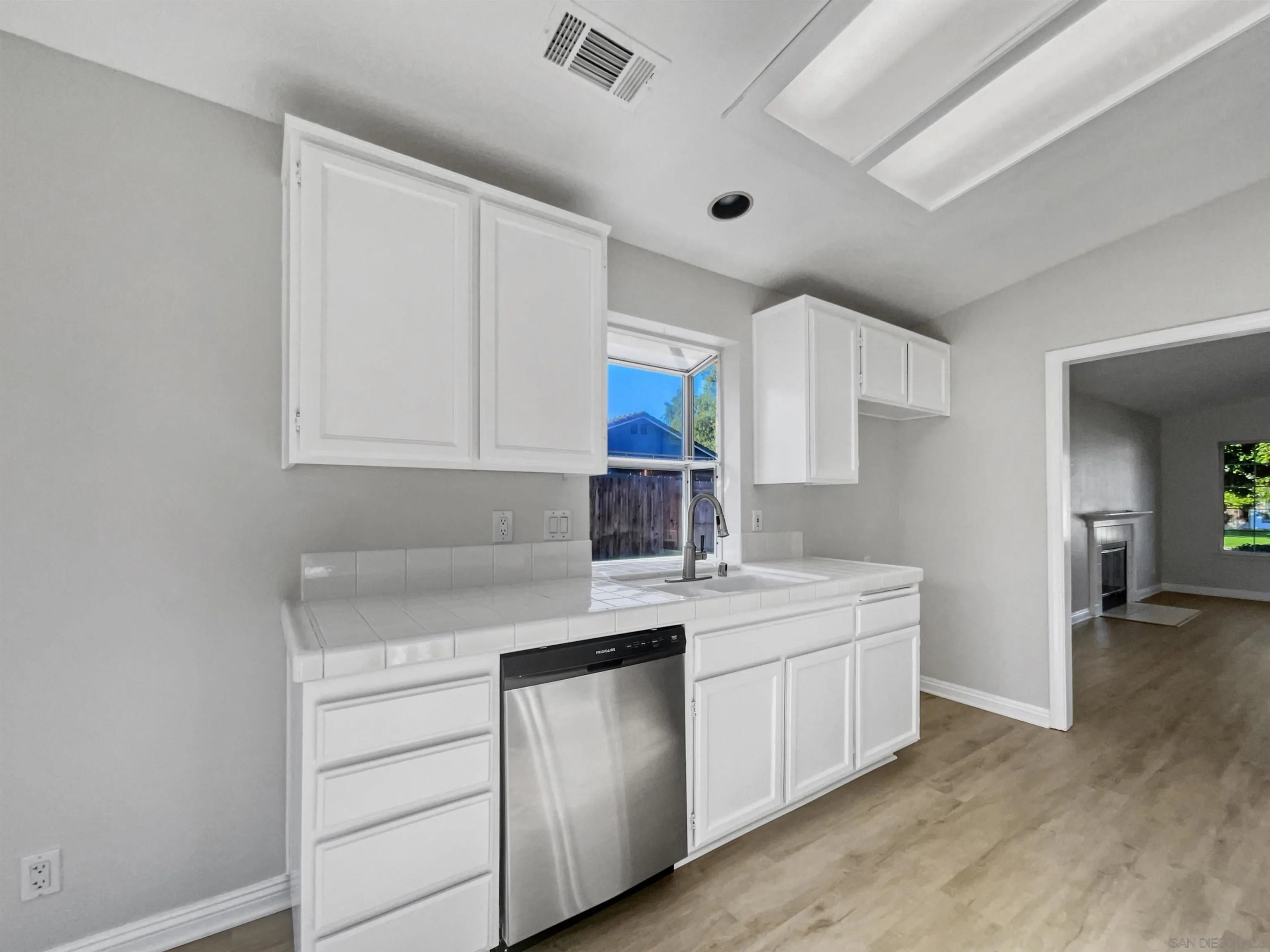 140 South Mercedes Road Fallbrook, CA 92028 - Photo 12 of 21 a kitchen with a sink dishwasher a stove and white cabinets with wooden floor