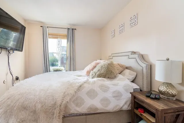 a bedroom with a bed and a flat tv screen on a dresser