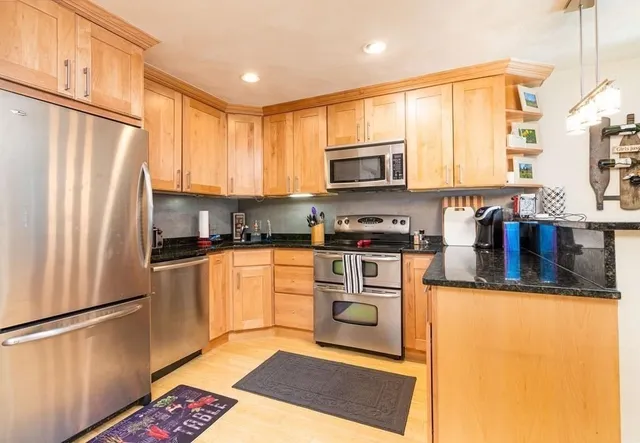 a kitchen with stainless steel appliances granite countertop a refrigerator a stove top oven a sink and dishwasher