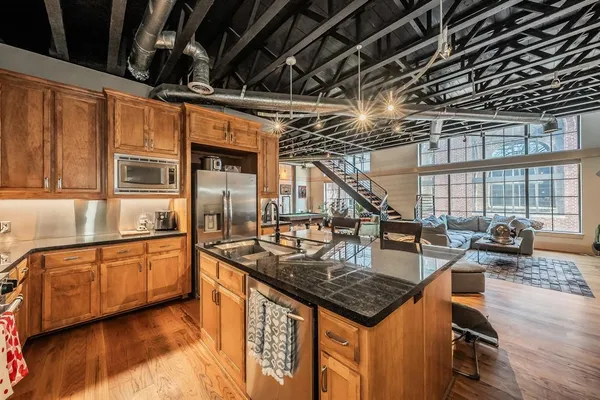 a kitchen with stainless steel appliances granite countertop a sink a stove and a wooden floors