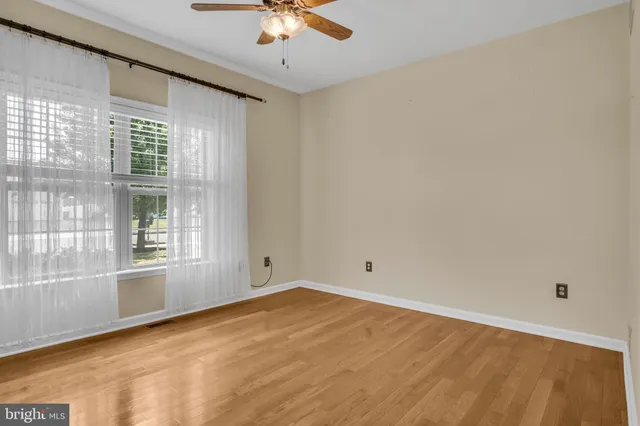 a view of empty room with wooden floor and window
