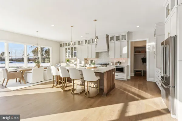 a large dining hall with stainless steel appliances kitchen island granite countertop a large cabinets and a dining table