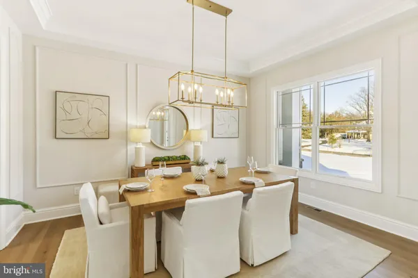 a dining room with wooden floor a chandelier a wooden table and chairs