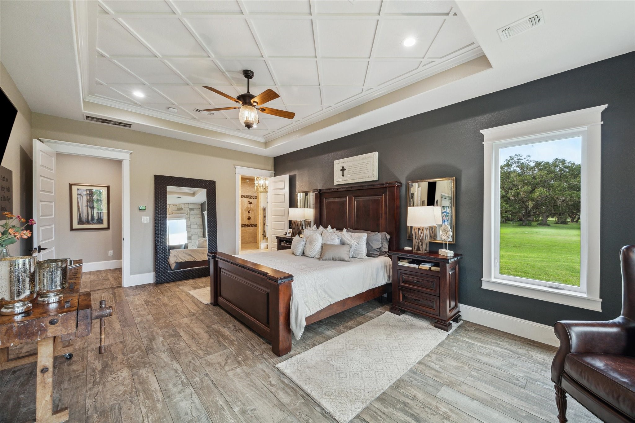 1255 Bronco Trail Angleton, TX 77515 - Photo 17 of 50 The oversized primary bedroom offers a spacious sitting area, creating a perfect retreat within the home. Four picture windows, framed with custom crown molding, fill the room with natural light and provide beautiful views. A private door leads to the rear covered patio, seamlessly extending the living space outdoors.