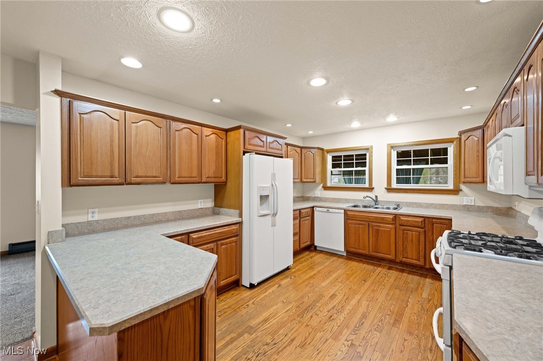 7590 Little Mountain Road Mentor, OH 44060 - Photo 13 of 40 Kitchen with recessed lighting, white appliances, a peninsula, a textured ceiling, and a sink