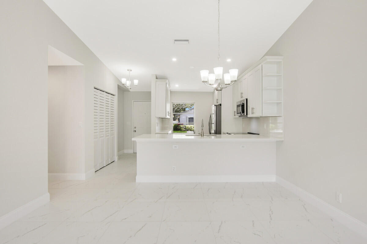 8641 Sunbird Place Boca Raton, FL 33496 - Photo 6 of 24 a view of a kitchen with kitchen island a sink wooden floor and living room view