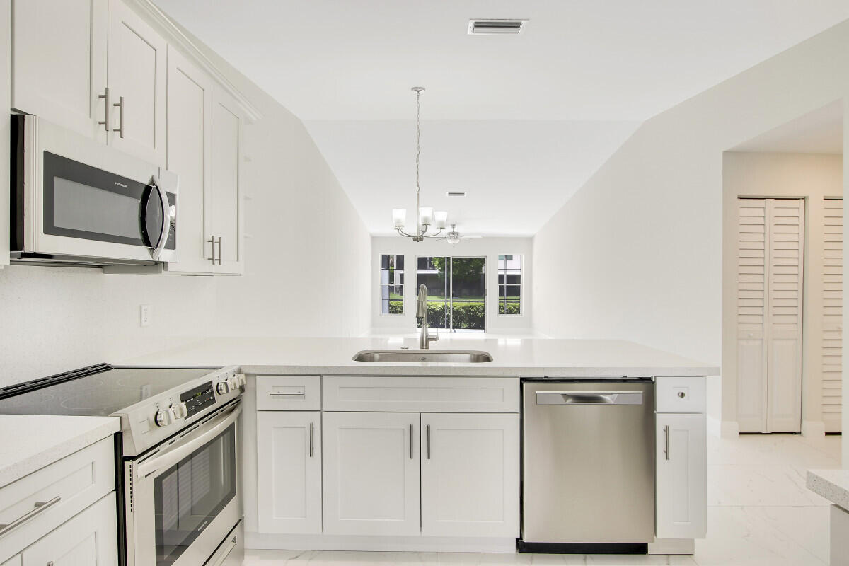 8641 Sunbird Place Boca Raton, FL 33496 - Photo 7 of 24 a kitchen with stainless steel appliances white cabinets and a sink