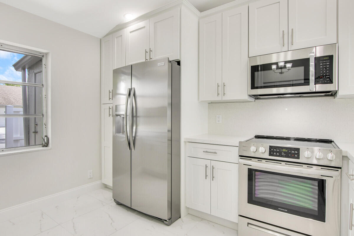 8641 Sunbird Place Boca Raton, FL 33496 - Photo 8 of 24 a kitchen with stainless steel appliances white cabinets and a stove