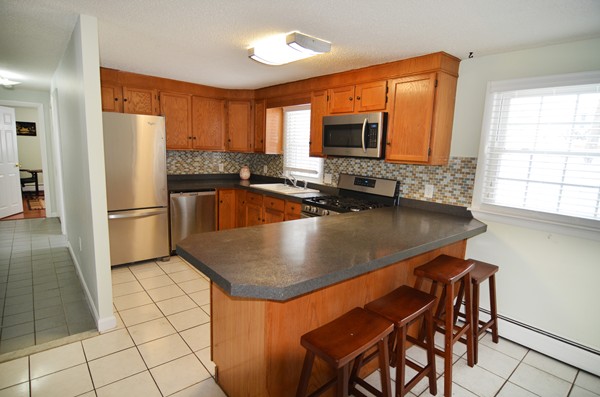 3 Eclipse Avenue Chelmsford, MA 01824 - Photo 3 of 6 a kitchen with stainless steel appliances granite countertop a sink a microwave and a refrigerator