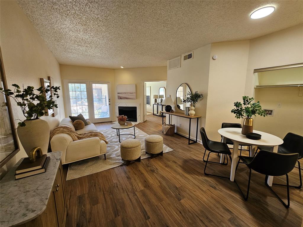 Open-concept living area featuring wood-finish flooring, a built-in fireplace, and double glass panel doors