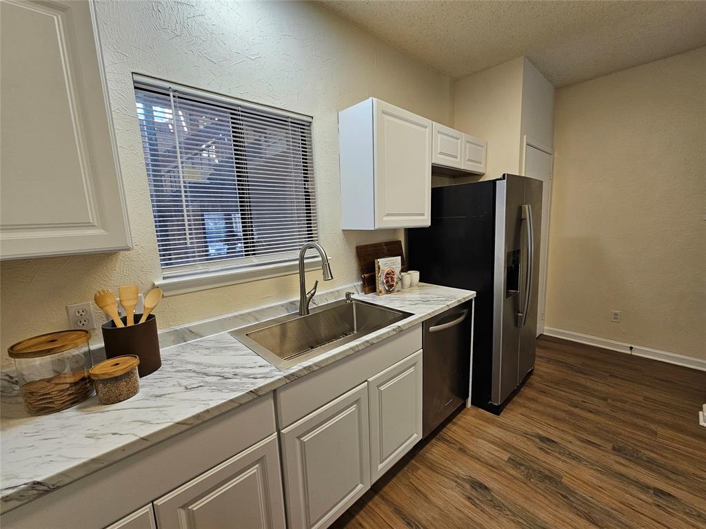 5550 Spring Valley Road, Unit C14 Dallas, TX 75254 - Photo 11 of 21 Kitchen featuring white cabinetry, gray veined countertops, and wood-finish flooring