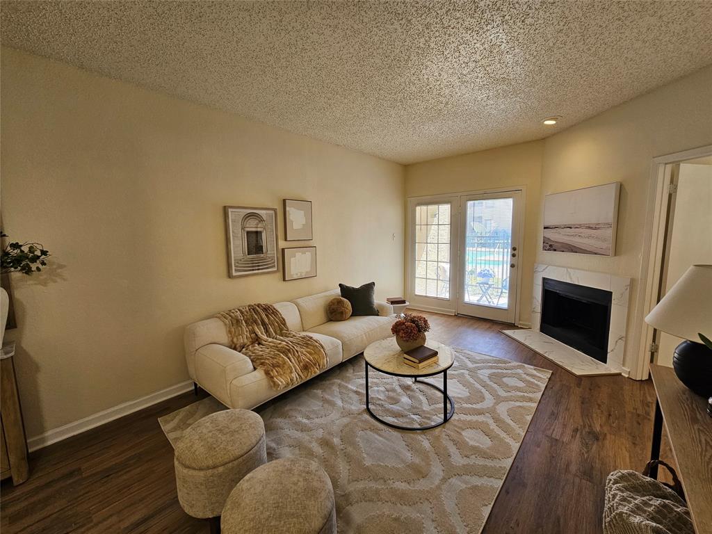 5550 Spring Valley Road, Unit C14 Dallas, TX 75254 - Photo 12 of 21 Living area featuring wood-finish flooring, a corner fireplace with a stone surround, and French doors
