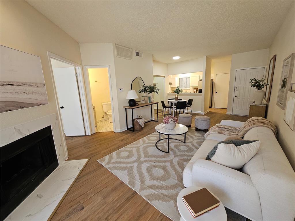 5550 Spring Valley Road, Unit C14 Dallas, TX 75254 - Photo 13 of 21 Living area featuring wood-finish flooring, a fireplace with a white tile surround, and recessed lighting