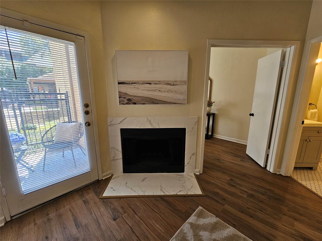 5550 Spring Valley Road, Unit C14 Dallas, TX 75254 - Photo 14 of 21 Living area featuring wood-finish flooring and a fireplace with a marble-look tile surround and hearth