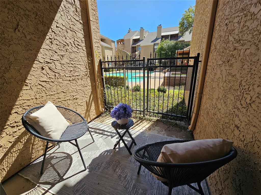 5550 Spring Valley Road, Unit C14 Dallas, TX 75254 - Photo 16 of 21 Private patio space featuring a textured stucco exterior and a wrought iron gate