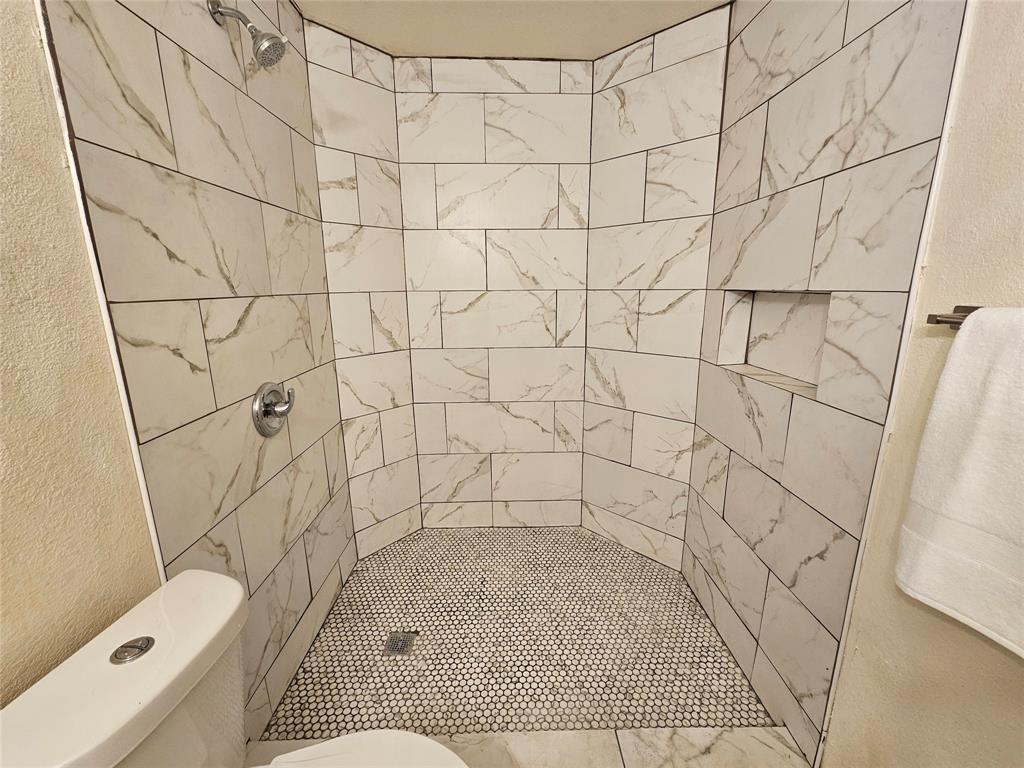 5550 Spring Valley Road, Unit C14 Dallas, TX 75254 - Photo 17 of 21 Walk-in shower with white marbled rectangular tiles, a built-in shower niche, and a honeycomb-patterned floor