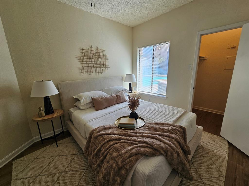 5550 Spring Valley Road, Unit C14 Dallas, TX 75254 - Photo 19 of 21 Bedroom featuring wood-finish flooring, a window offering exterior views, and an open closet space