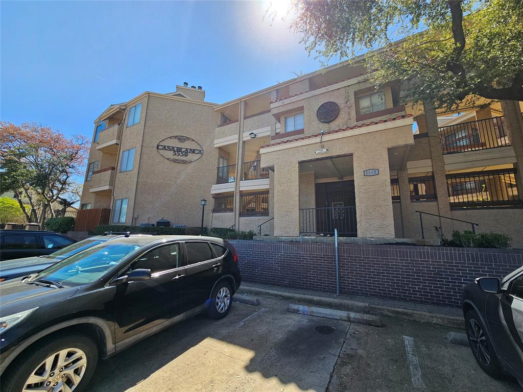 5550 Spring Valley Road, Unit C14 Dallas, TX 75254 - Photo 2 of 21 Multi-story residential building featuring a stucco exterior, multiple private balconies, and a brick facade base