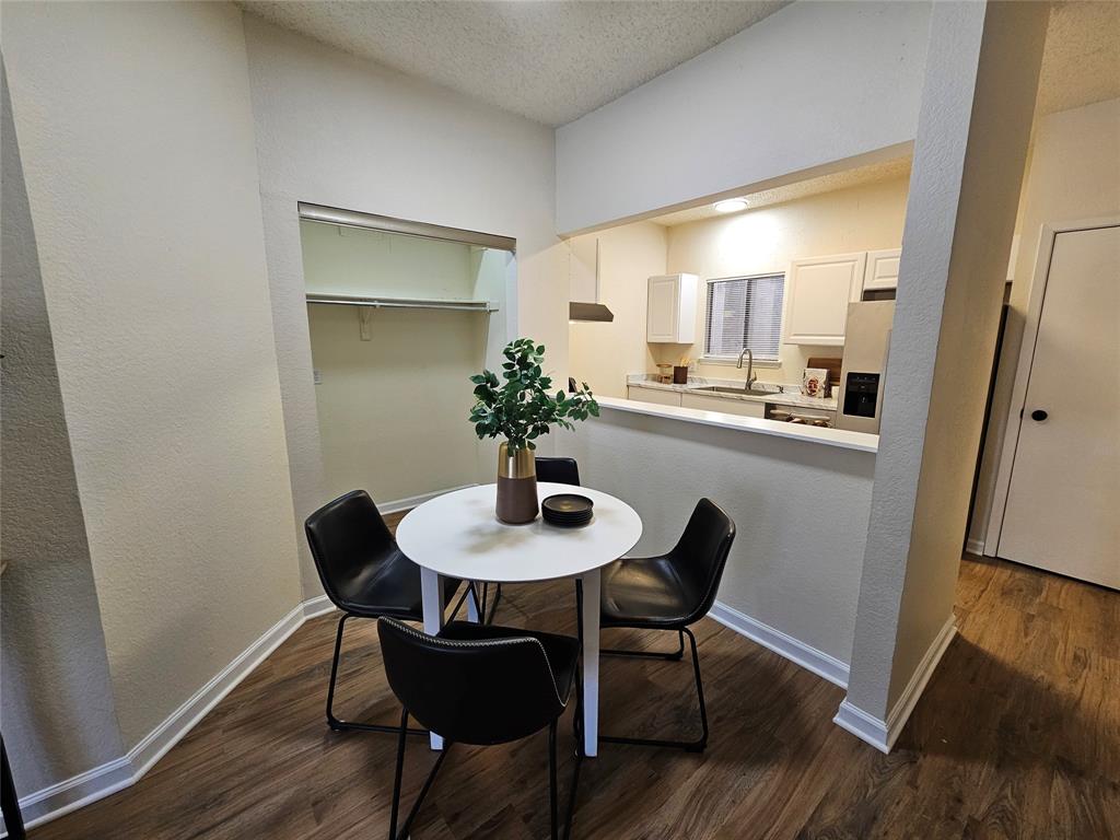 5550 Spring Valley Road, Unit C14 Dallas, TX 75254 - Photo 7 of 21 Dining area featuring wood-finish flooring, a kitchen pass-through, a built-in closet with shelving and a hanging rod, and white baseboards