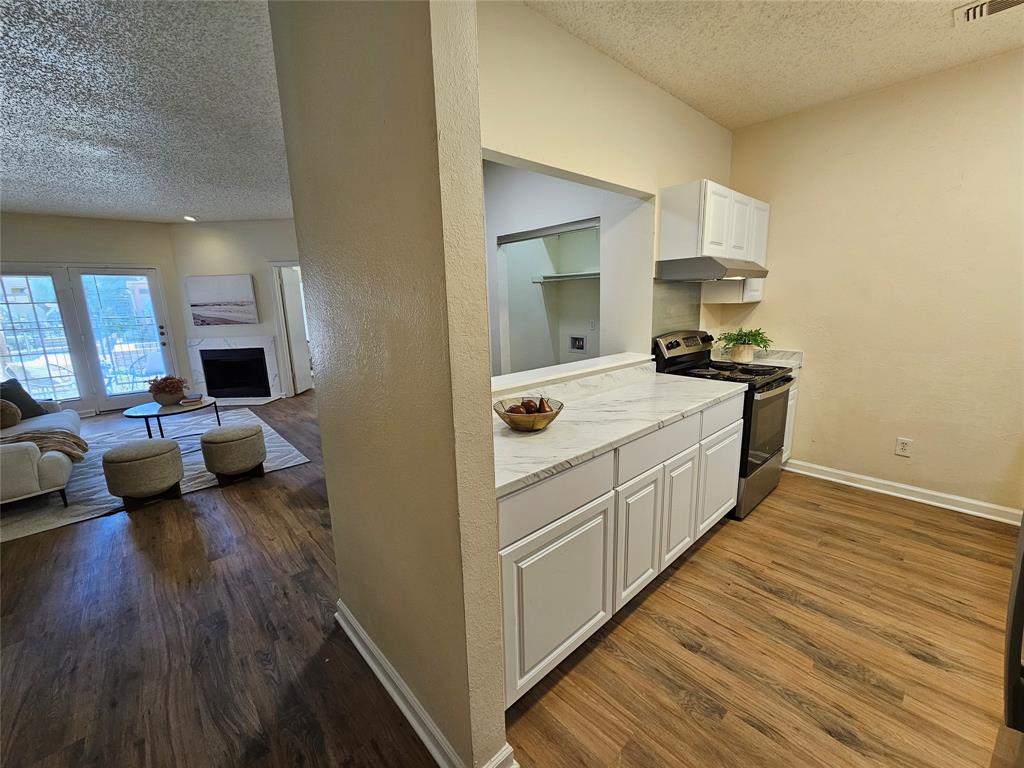 5550 Spring Valley Road, Unit C14 Dallas, TX 75254 - Photo 8 of 21 Kitchen pass-through with white cabinetry, light-toned countertops, and wood-finish flooring
