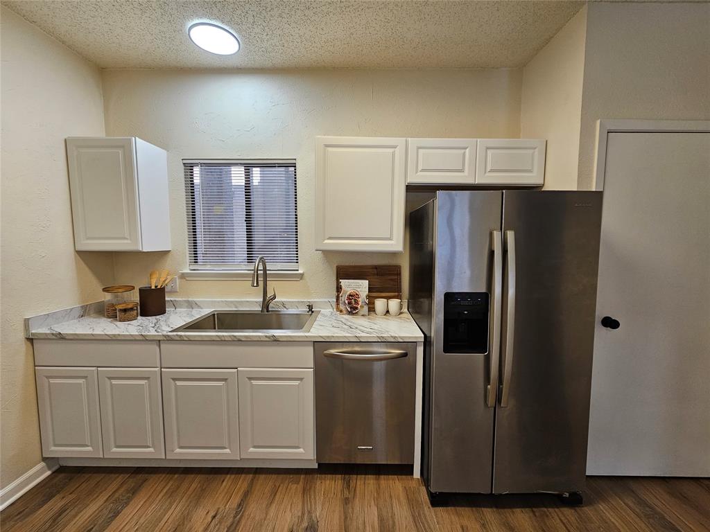 5550 Spring Valley Road, Unit C14 Dallas, TX 75254 - Photo 9 of 21 Kitchen featuring wood-finish flooring, white cabinetry, a stainless steel sink with a high-arc faucet, and light-toned countertops