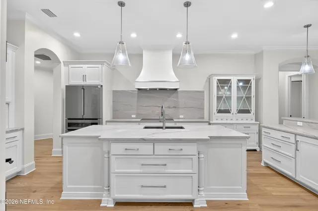 a large kitchen with granite countertop a large kitchen island white cabinetry and refrigerator