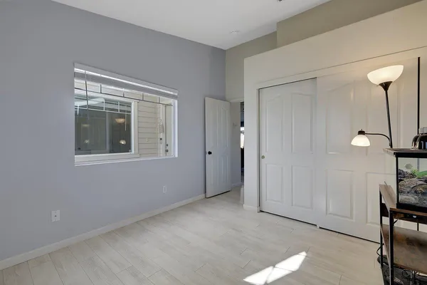 a view of an empty room with a window and wooden floor