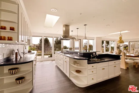 a kitchen with kitchen island granite countertop a sink and white cabinets