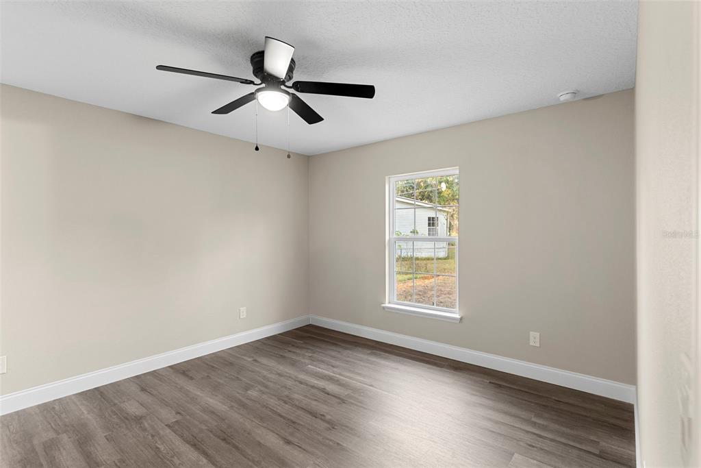603 Moose Lodge Road, Unit A Bartow, FL 33830 - Photo 12 of 22 an empty room with wooden floor ceiling fan and windows