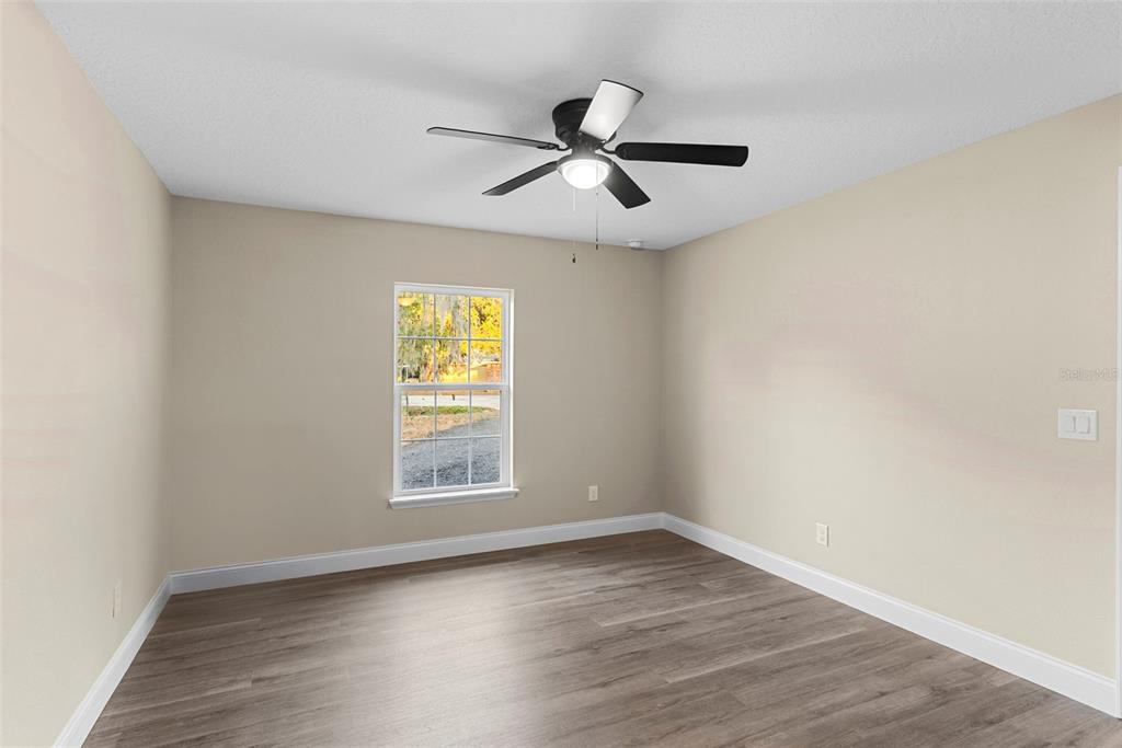 603 Moose Lodge Road, Unit A Bartow, FL 33830 - Photo 13 of 22 an empty room with wooden floor ceiling fan and windows