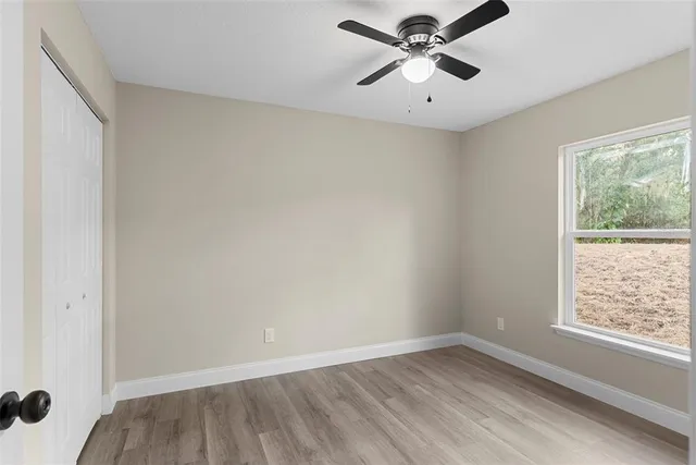 an empty room with a window and a fan