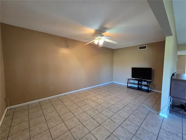 an empty room with windows and ceiling fan