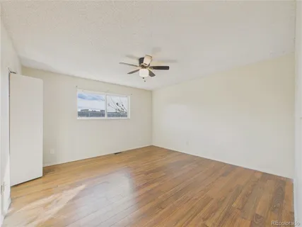 an empty room with a ceiling fan and wooden floor